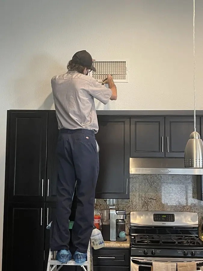 Technician inspecting an air vent during HVAC service in Apple Valley